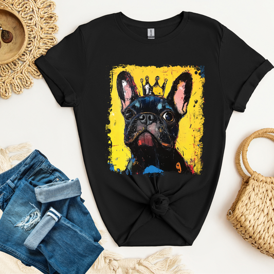 Black t-shirt with a colorful French Bulldog graphic on a white surface with denim shorts and a woven bag.
