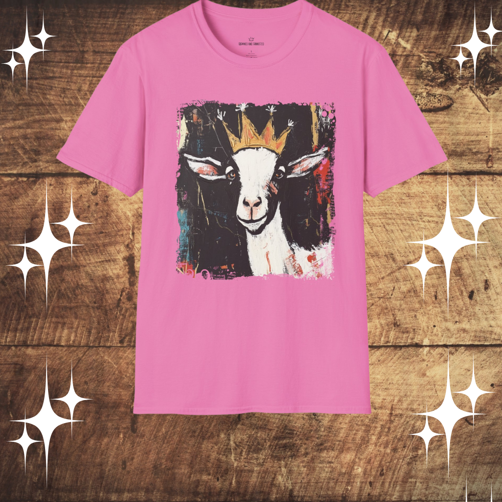 Pink t-shirt with a goat graphic wearing a crown on a wooden surface